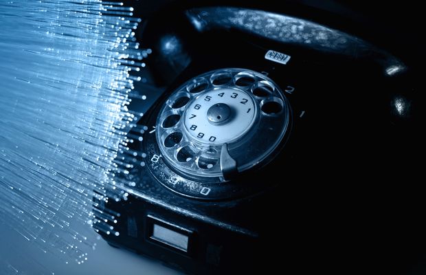 An old rotary telephone lit by strands of optical fibre