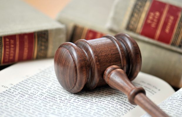A wooden gavel lying on an open law book