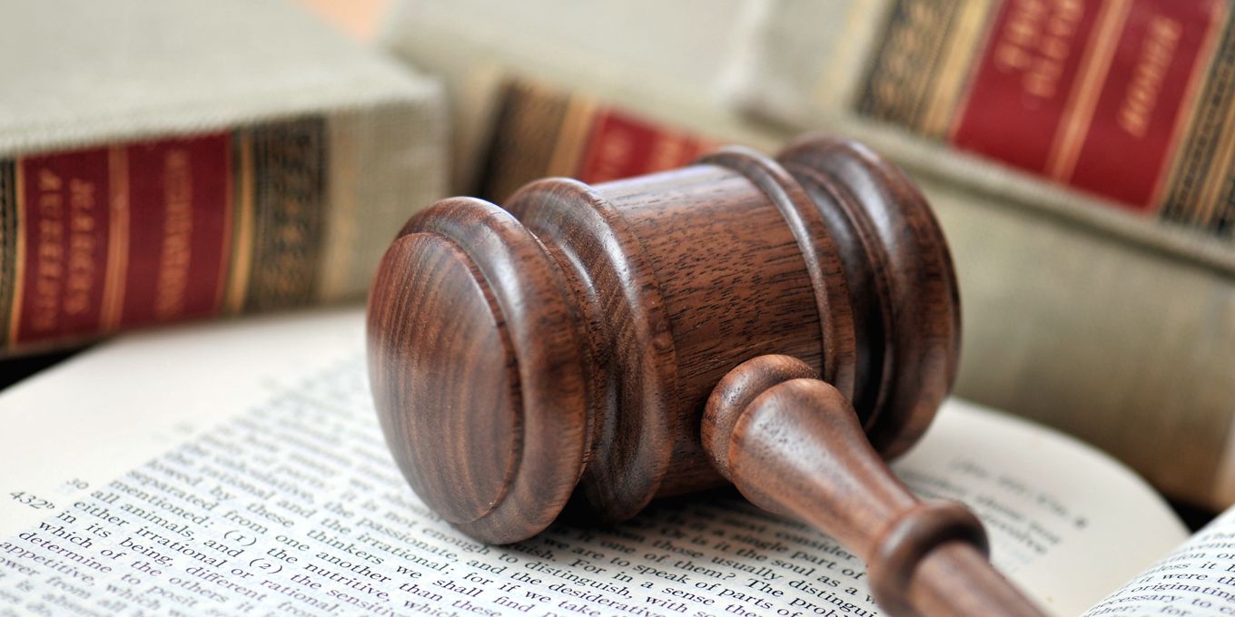 A wooden gavel lying on an open law book