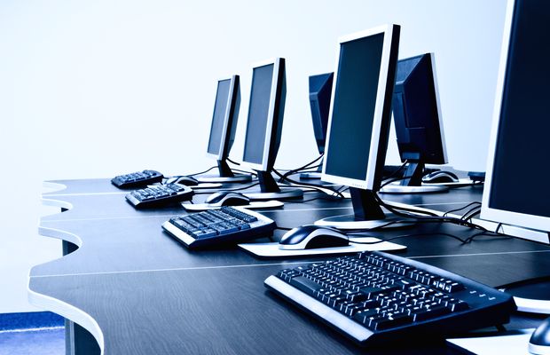Computer monitors and keyboards lined up along a white desk